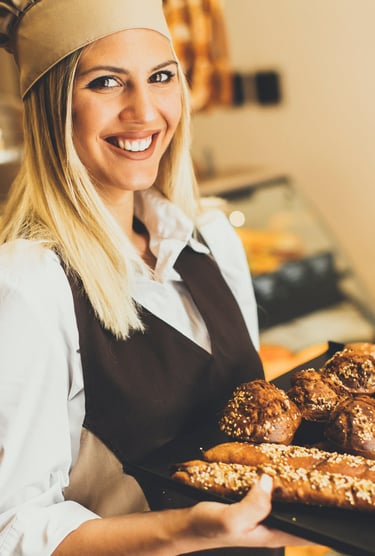 Femme debout qui tient un plateau  remplie de viennoiserie 