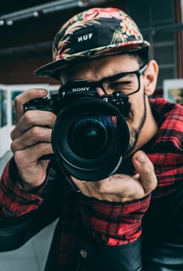 Un homme à lunette et casquette qui prend une photo