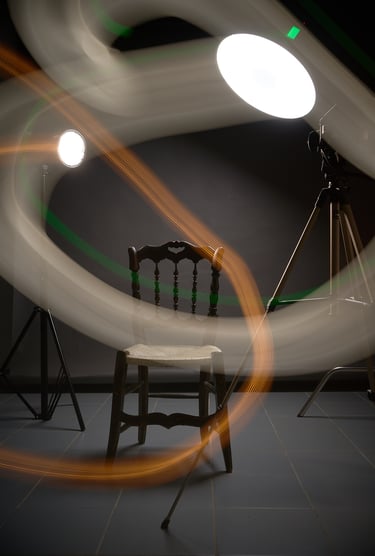 A wooden chair in a dark studio with abstract light painting trails and photography studio lights.