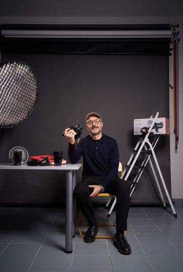 Professional photographer holding a camera in a studio with lighting equipment and lenses.