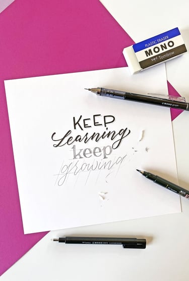 Hand lettering on white paper with a Tombow eraser and pens, featuring the quote Keep Learning Keep Growing.