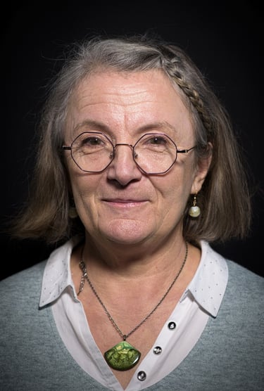 a woman with glasses and a necklace with a green pendant