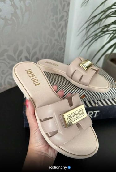 a person holding a pair of shoes with a gold buckle
