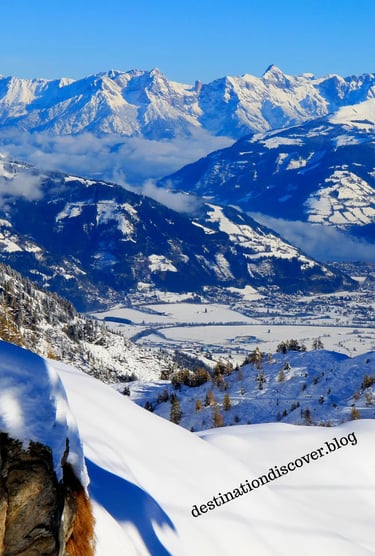 Breathtaking panorama of the Austrian Alps, featuring vast snow-covered peaks and a clear blue sky.