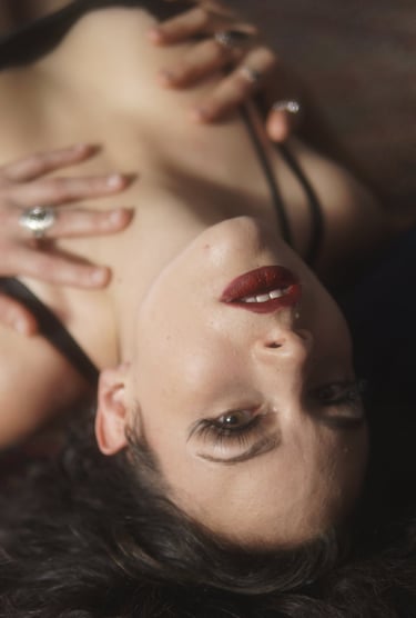 a woman in a black lingersuite laying down with red lipstick