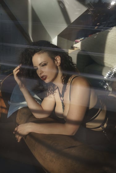 a woman in black lingerie suit on a sofa seen through a window