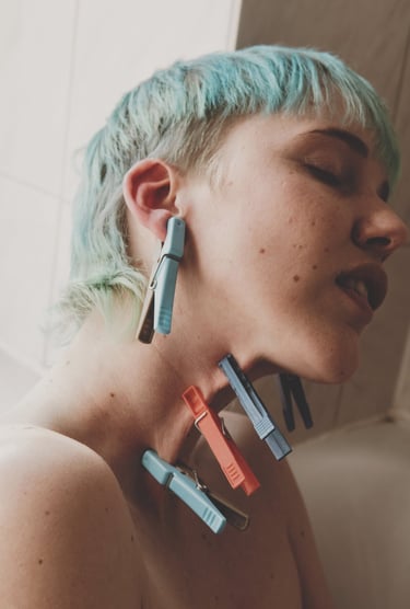 a woman with blue hair and clothespins on her skin