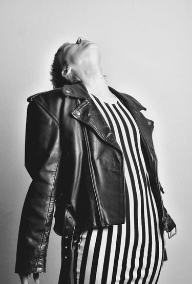 a woman in a striped dress and leather jacket posing for a photo