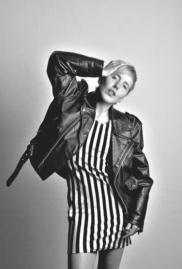 a woman in a striped dress and leather jacket posing for a photo