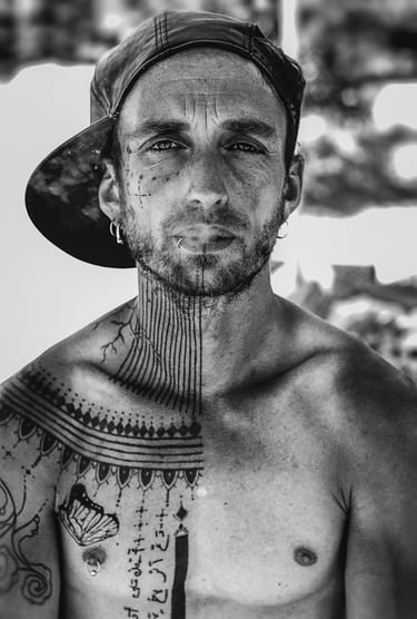 a man with tattoos on his chest and neck, a cap and smoke goes out og his mouth