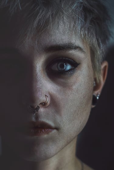 a woman with piercings blue eyes lipstick, half face in shadow half in light