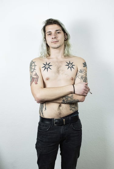 a man with tattoos on his chest posing for a photo