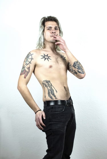 a man with tattoos on his chest, smoks, posing for a photo