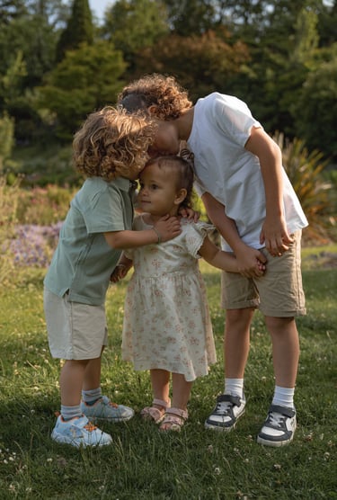 two brother kissing and hugging little sister holding hands