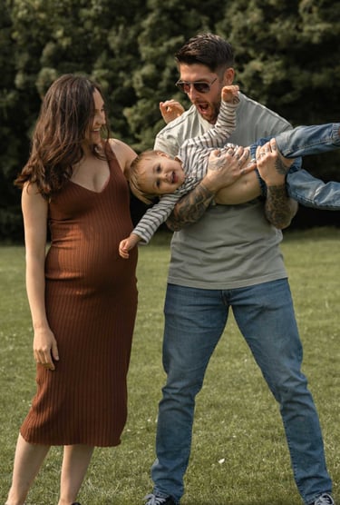 Pregnant woman laughing father is lifting his son