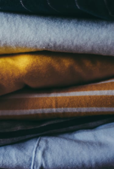 Close-up of neatly folded clothes in soft fabrics and warm colors.