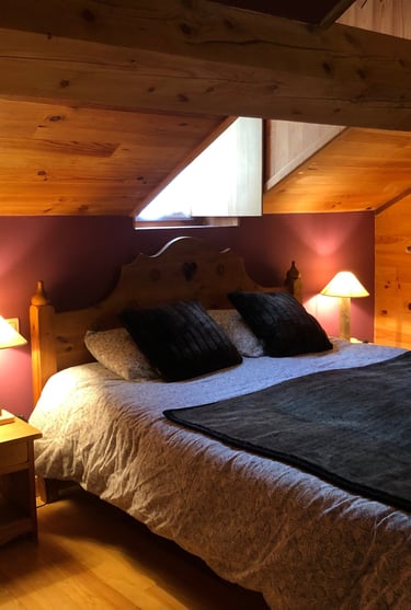 a bedroom in the Russell barn with a mountain-style bed two bedside tables and two wooden lamps
