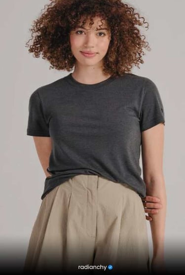 a woman with curly hair and a grey t - shirt