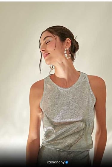 a woman with a silver top and earrings