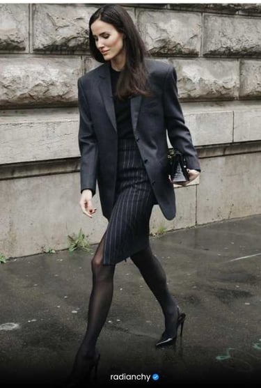 a woman in a suit and heels walking down a street