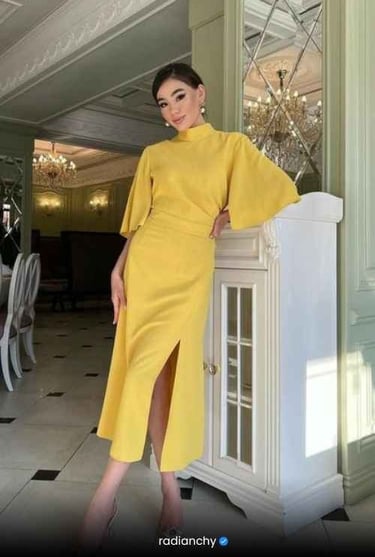 a woman in a yellow dress standing in front of a cabinet