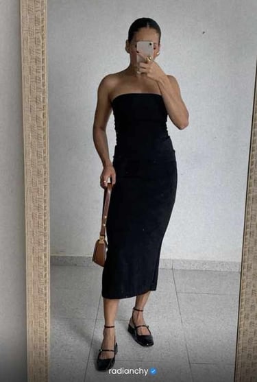 a woman in a black dress standing in front of a mirror