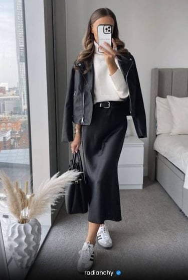 a woman in a black leather jacket and white sneakers