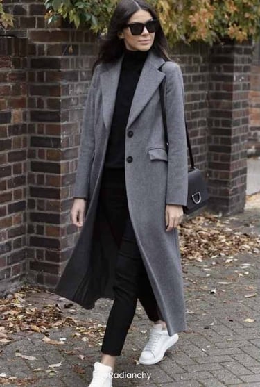a woman in a grey coat and white sneakers