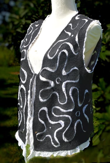Handmade black nuno felted wool vest with white floral swirl patterns on a mannequin.