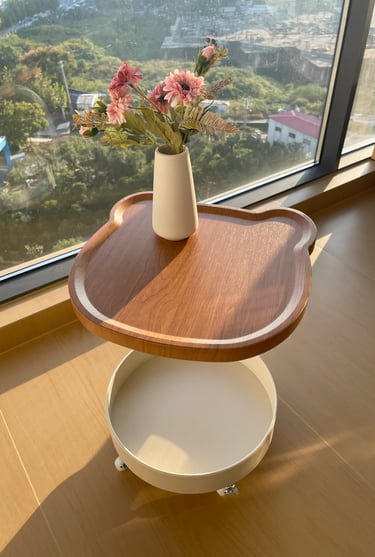 Wooden small side table by a window with flowers, ideal for a cozy balcony reading corner or outdoor