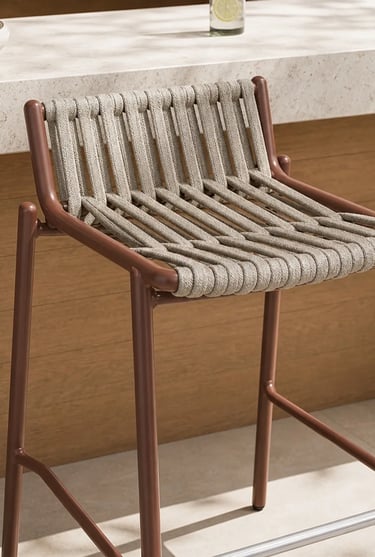 Close-up of a woven outdoor chair with a slim frame, designed for comfortable balcony seating and sm