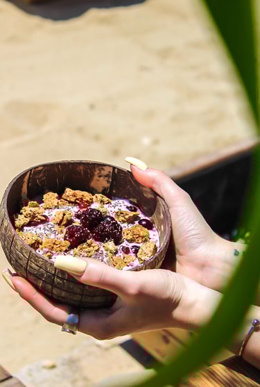 a person holding a coconut bowl of with greek yoghurt, granola and fruit