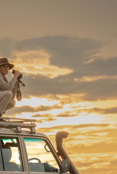 Woman with binoculars with dramatic sunset behind