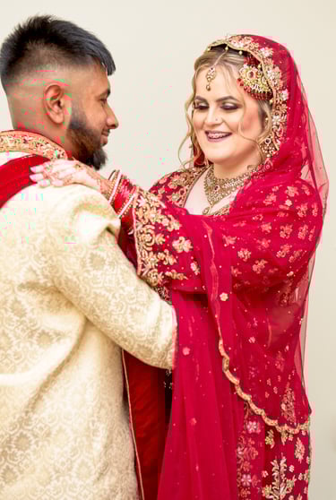 candid photo of bride and asian groom, bride's hand on groom shoulder, both laughing and having a good time