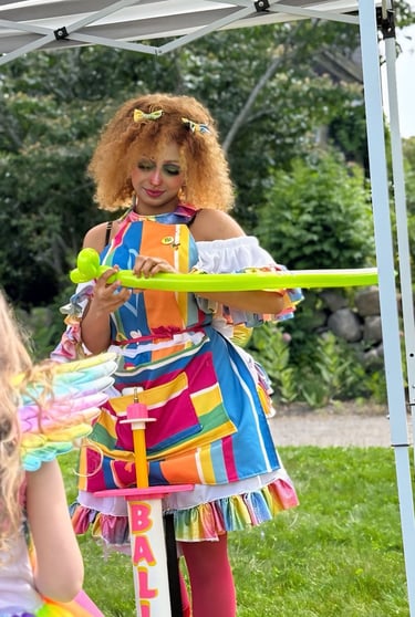 Balloon twister dressed in rainbow making a new shape