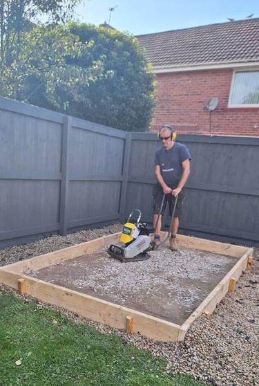 a man compacting a base for a shed
