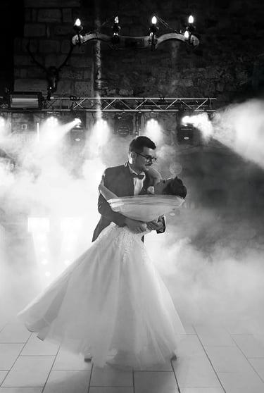 Marié portant sa femme dans ses bras lors de leur ouverture de bal, entourés de fumée et lumières.