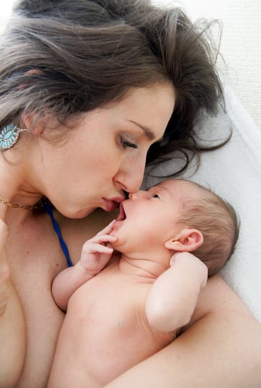 jeune maman allongée avec son bébé dans les bras lors d'une séance photo