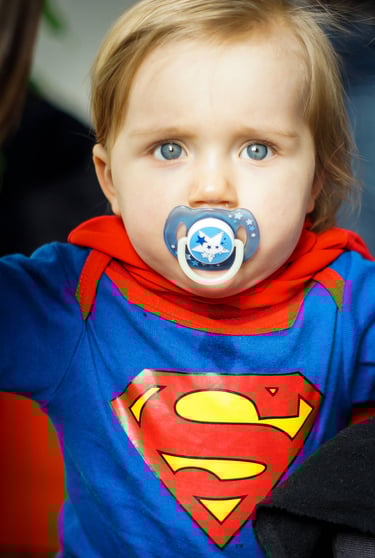 Bébé avec un pyjama Superman, sucette et yeux bleus. Super héro naissance.