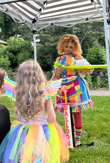Balloon twister dressed in rainbow making a new shape