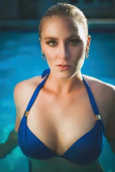 A girl in a blue string bikini in the pool staring straight 