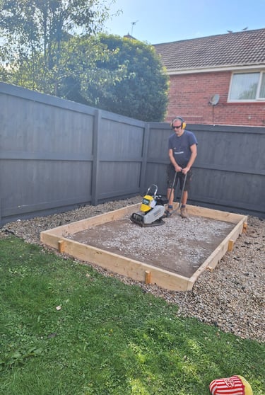 a man compacting a base for a shed