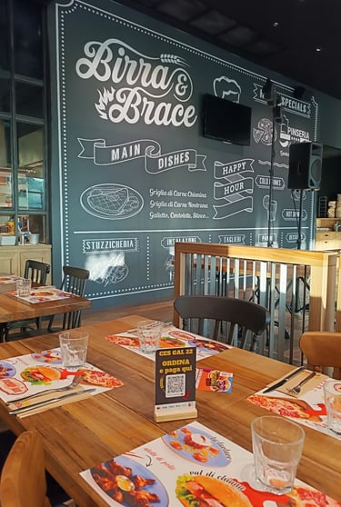 Interni del Birra & Brace con parete illustrata dedicata alle specialità del locale.