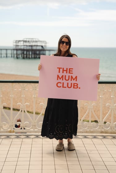 woman smiling holding a big sign on the seafront