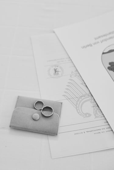 Wedding rings lying on a small bag next to marriage certificates.