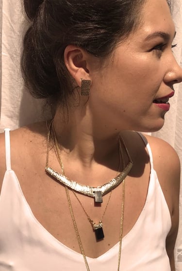 uma mulher veste uma blusa branca com um mix de colares com cristas e obsidiana negra