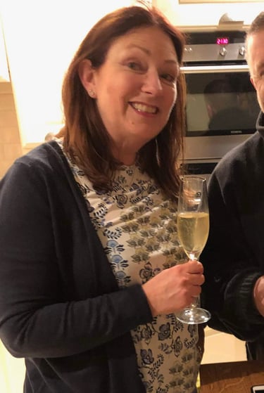 Two adults celebrating birthday in modern kitchen with champagne and cake reading 'Happy Birthday