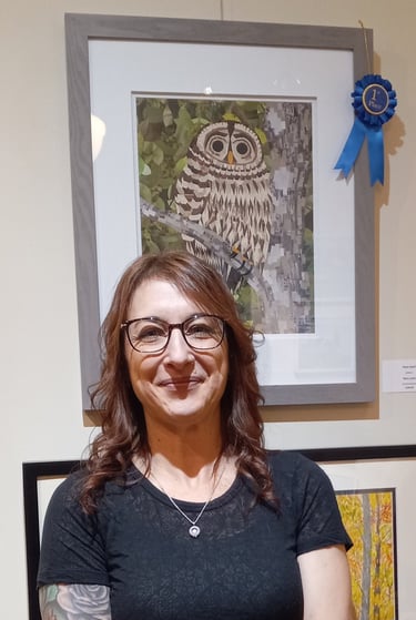 Artist smiling in front of her first-place award-winning owl mosaic artwork at an art gallery.