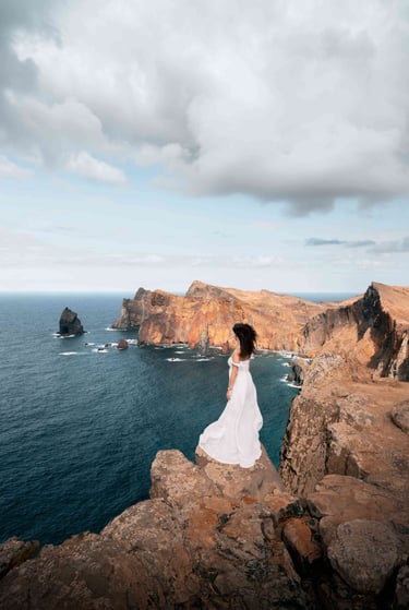 A photo of a young woman standing on the cliffs overlooking the ocean