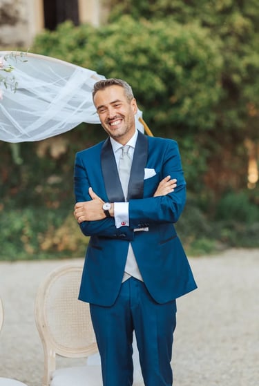 Marié ému et souriant pendant la découverte de sa future épouse, devant une arche fleurie.